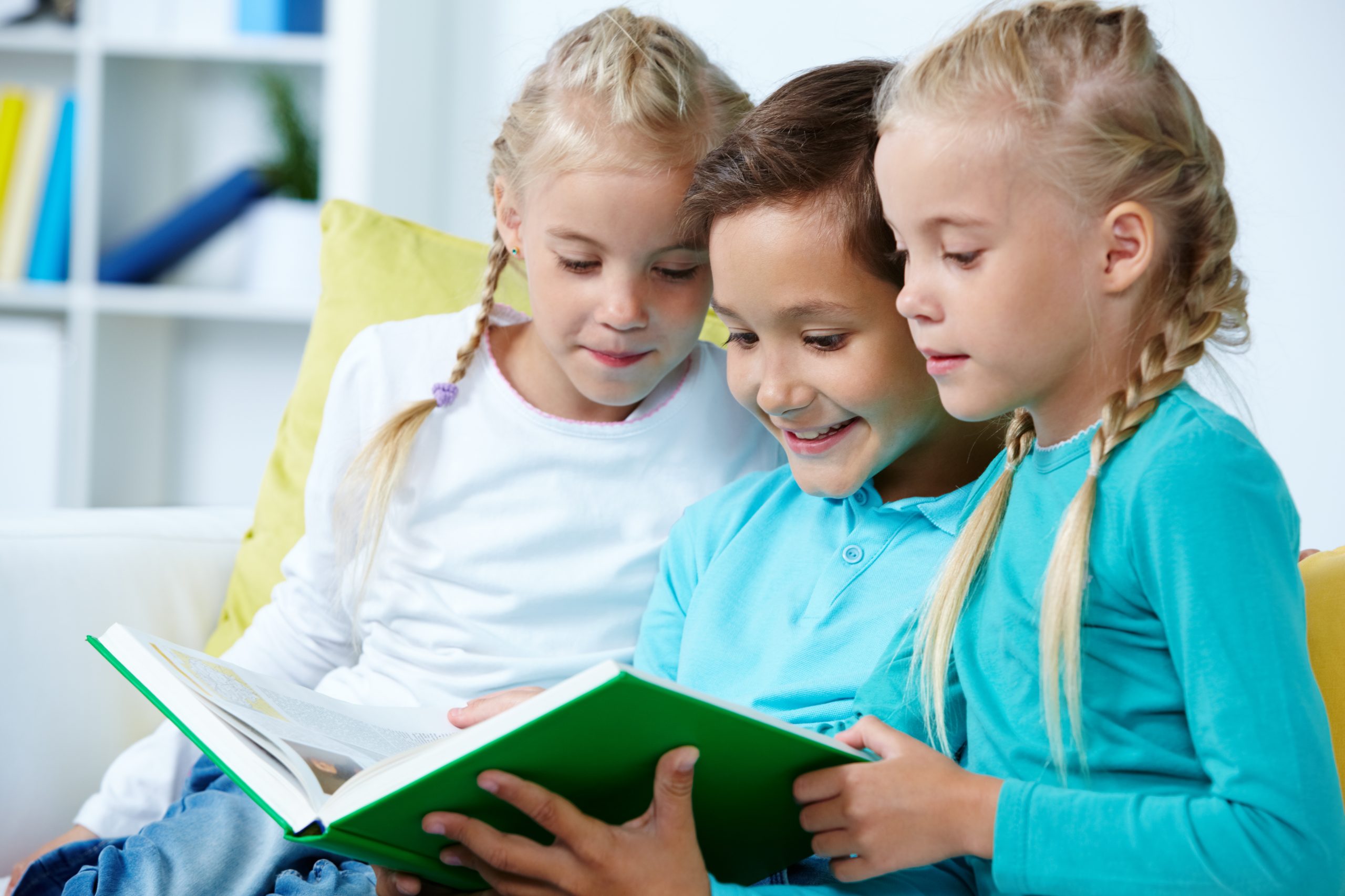 Smart schoolboy and twin girls reading book